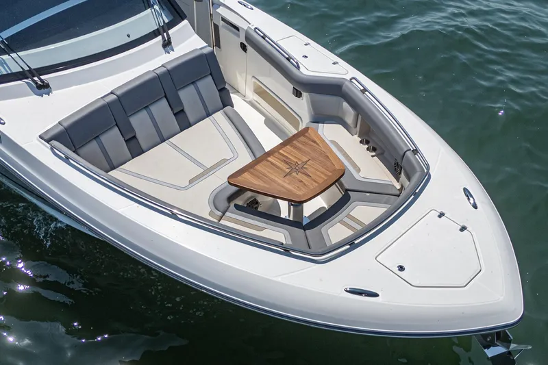 Slide: The Image of 2024 Boston Whaler 380 Realm boat with elegant seating and wooden table on calm water. - 26