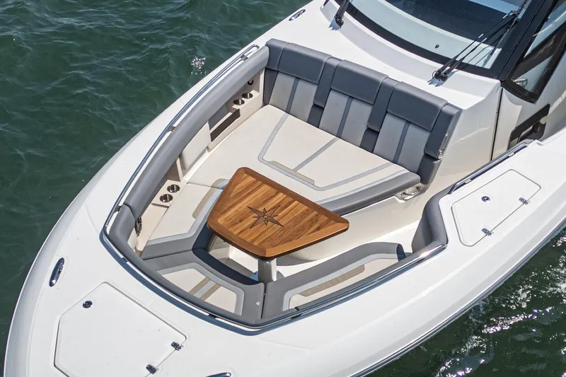Slide: The Image of 2024 Boston Whaler 380 Realm boat with sleek seating and wooden table on deck. - 27