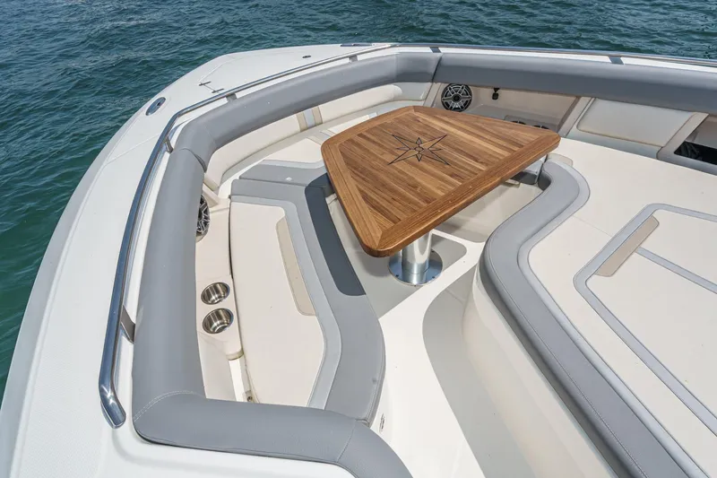 Slide: The Image of 2024 Boston Whaler 380 Realm boat interior with elegant wooden table and cushioned seating. - 29