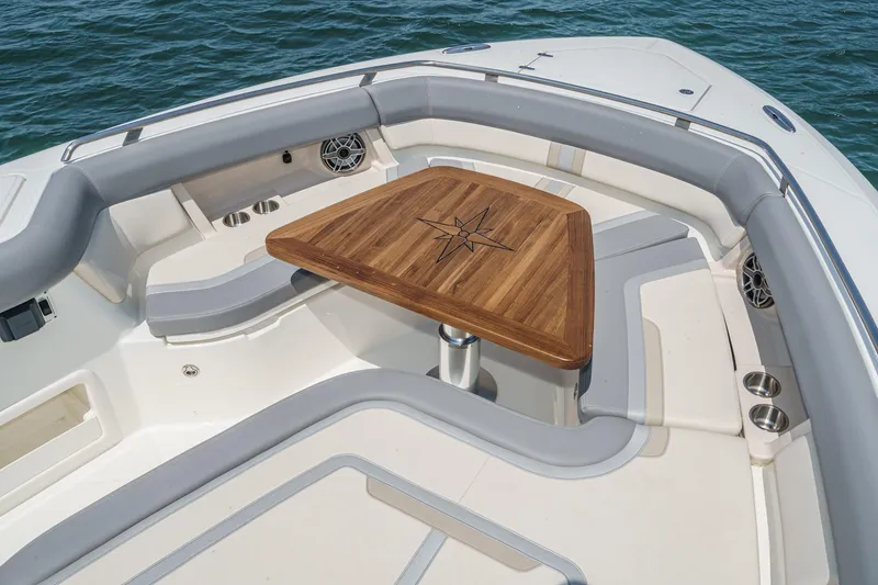 Slide: The Image of 2024 Boston Whaler 380 Realm boat interior with wooden table and cushioned seating. - 30