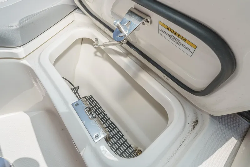 Slide: The Image of Storage compartment on 2024 Boston Whaler 380 Realm boat, featuring secure latch and caution label. - 35