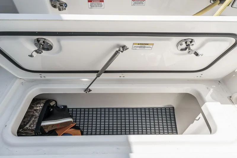 Slide: The Image of 2024 Boston Whaler 380 Realm storage compartment with open lid and gear inside. - 51