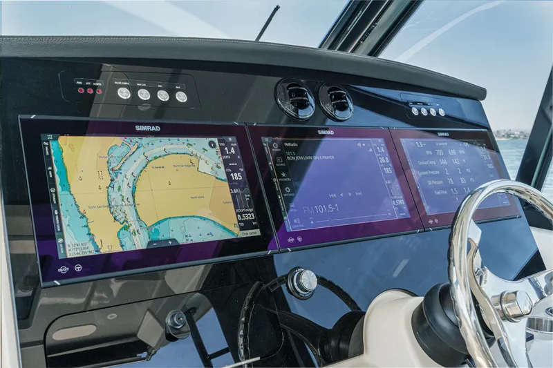 Slide: The Image of 2024 Boston Whaler 380 Realm dashboard with Simrad navigation displays and steering wheel. - 62