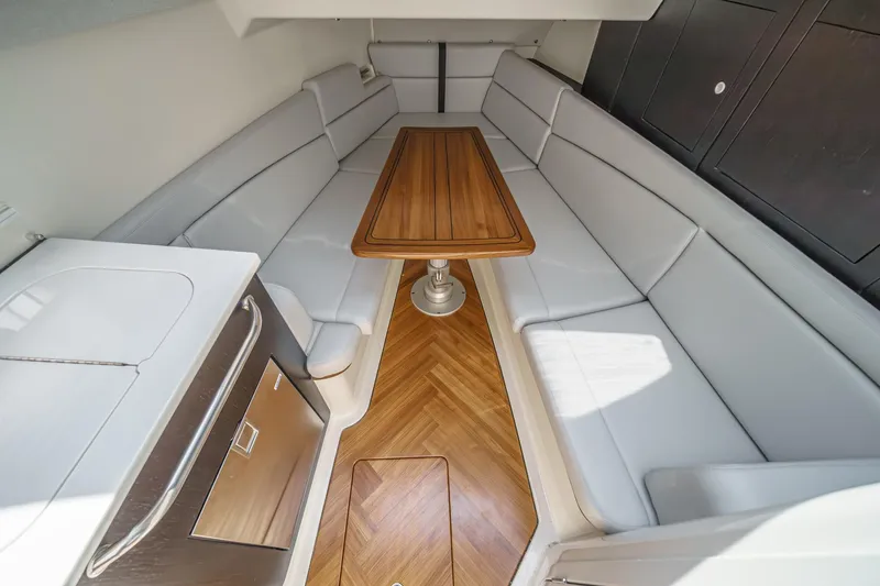 Slide: The Image of 2024 Boston Whaler 380 Realm interior with elegant seating and wooden table. - 69