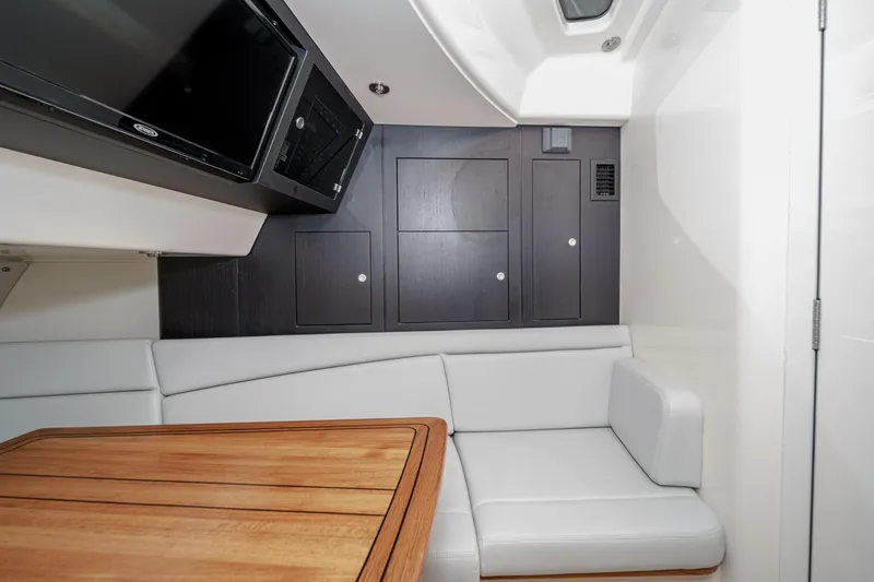 Slide: The Image of 2024 Boston Whaler 380 Realm interior with white seating and wooden table. - 70