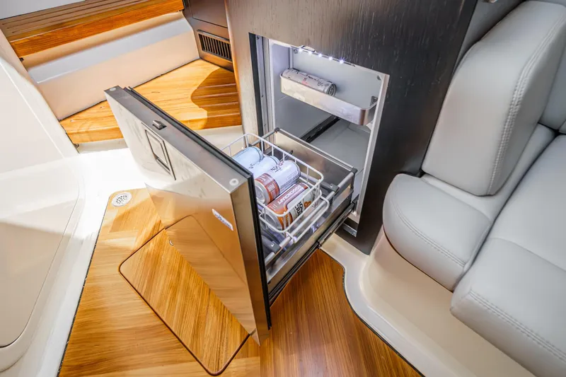 Slide: The Image of 2024 Boston Whaler 380 Realm interior with open fridge, showcasing luxury seating and wood flooring. - 74