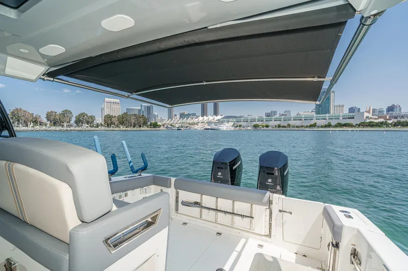 Slide: The Image of 2024 Boston Whaler 380 Realm boat with city skyline view, featuring dual engines and shaded seating. - 85