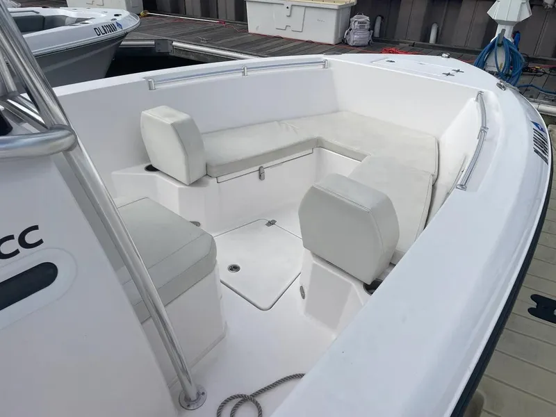 Slide: The Image of 2023 Aquasport 22CC boat with white cushioned seating at the dock. - 16