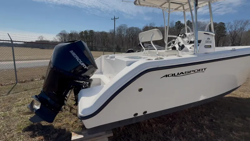 Slide: The Image of 2023 Aquasport 22CC boat with Mercury outboard motor, parked outdoors. - 9