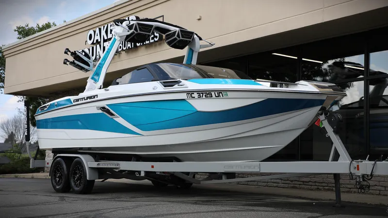 Slide: The Image of 2021 Centurion Ri245 boat on trailer outside dealership, featuring sleek blue and white design. - 5