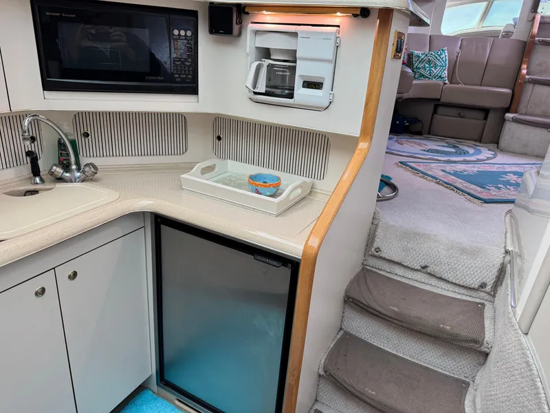 Slide: The Image of 1998 Sea Ray 420 Aft Cabin kitchen with microwave, sink, and stairs to seating area. - 22