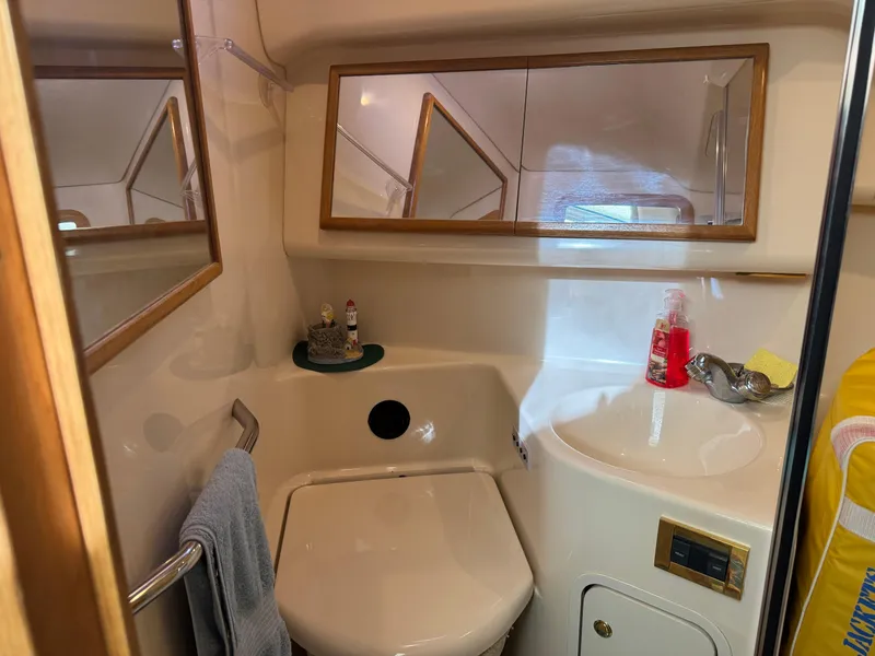Slide: The Image of 1998 Sea Ray 420 Aft Cabin bathroom with sink, mirror, and toiletries. - 25