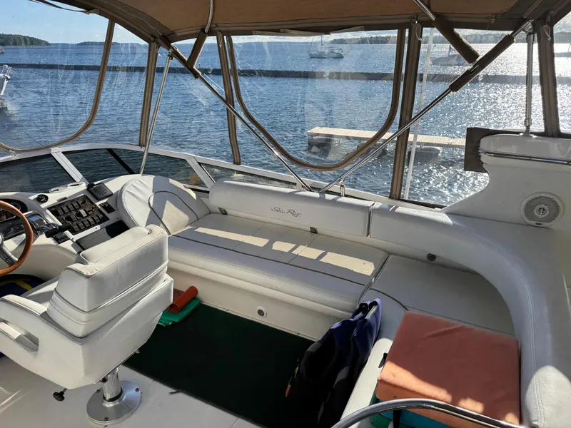 Slide: The Image of 1998 Sea Ray 420 Aft Cabin interior with helm and seating, overlooking serene water. - 8