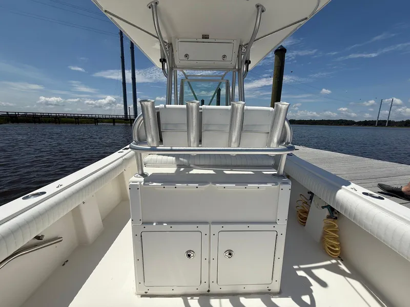 Slide: The Image of 2006 Regulator 26 Forward Seating boat interior with rod holders, docked by calm water. - 10