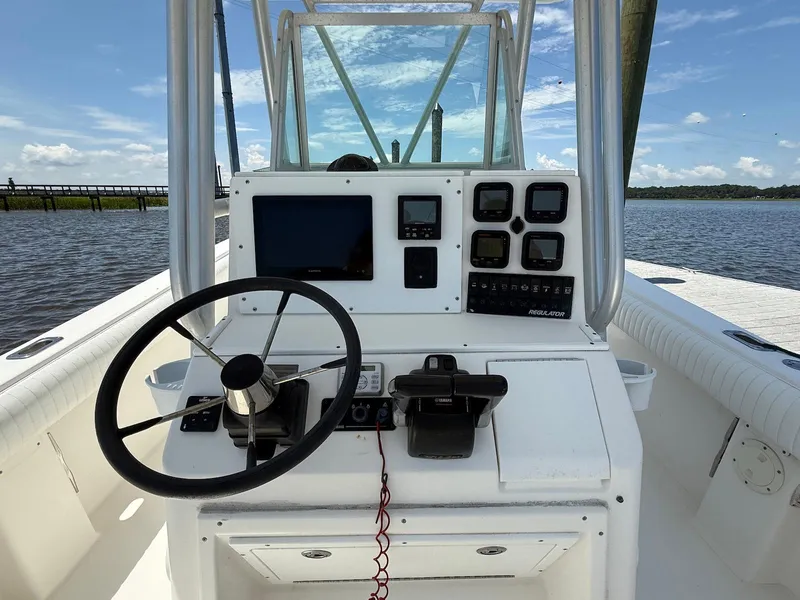 Slide: The Image of 2006 Regulator 26 Forward Seating boat dashboard with steering wheel and control panel on water. - 11