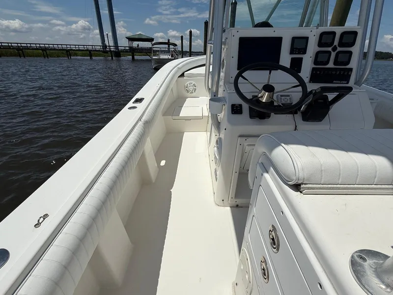 Slide: The Image of 2006 Regulator 26 Forward Seating boat interior with steering console, white seating, and water view. - 13