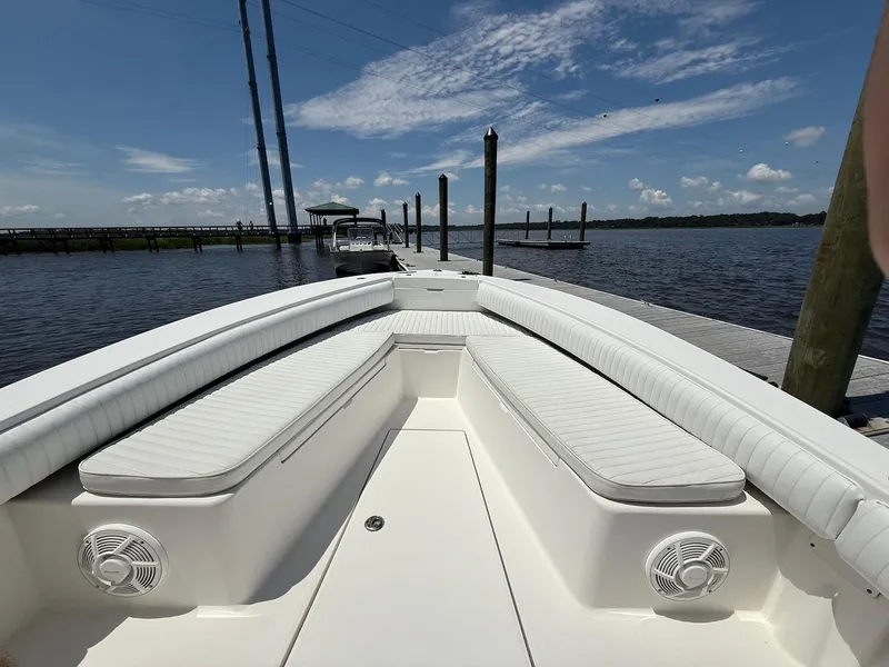 Slide: The Image of 2006 Regulator 26 Forward Seating boat docked by a serene waterfront under a clear blue sky. - 18