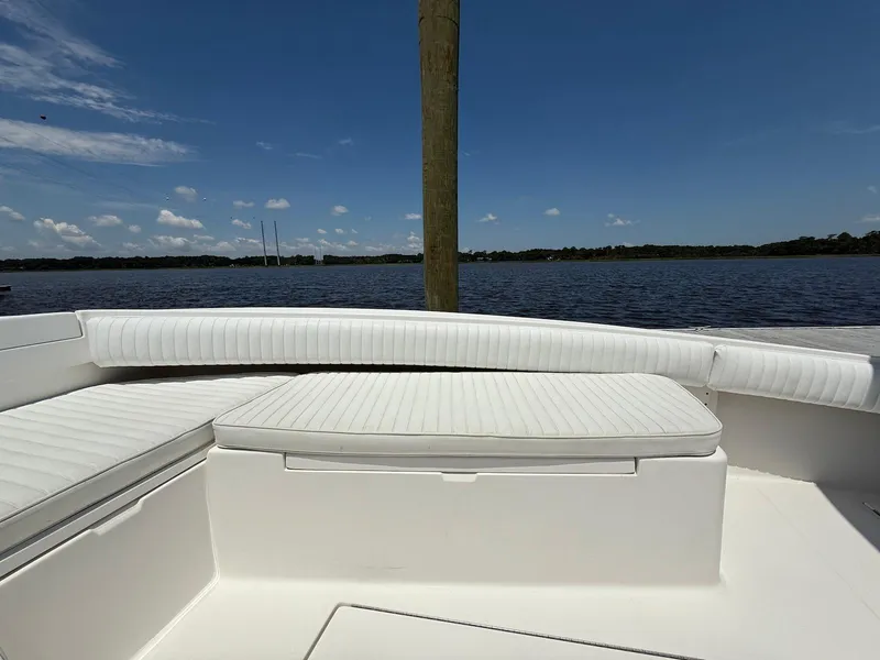 Slide: The Image of 2006 Regulator 26 Forward Seating boat with white cushions, overlooking calm water and blue sky. - 19