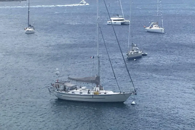 Slide: The Image of Sailboats anchored in calm waters, featuring a 2004 Pacific Seacraft 40. - 2