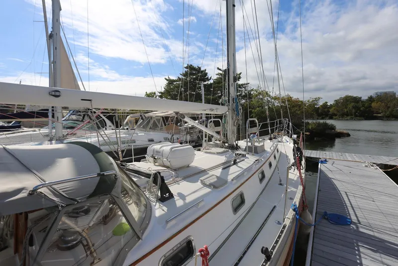 Slide: The Image of 2004 Pacific Seacraft Crealock 40 sailboat docked by a serene waterfront. - 26