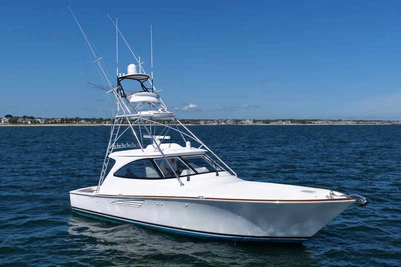 Slide: The Image of 2024 Viking 48 Sport Tower yacht on open water under clear blue sky. - 20