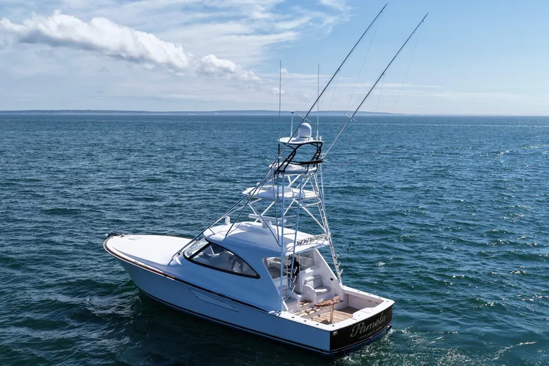 Slide: The Image of 2024 Viking 48 Sport Tower yacht cruising on open sea under clear skies. - 14