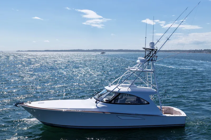 Slide: The Image of 2024 Viking 48 Sport Tower yacht cruising on open water under clear skies. - 16