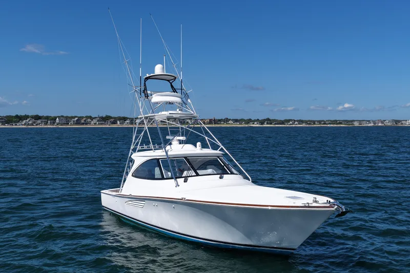 Slide: The Image of 2024 Viking 48 Sport Tower yacht on open water under clear blue sky. - 19