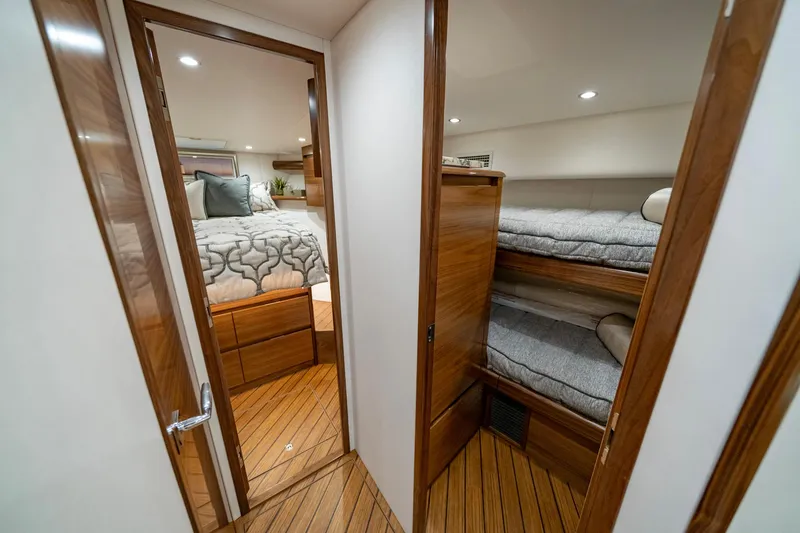 Slide: The Image of 2024 Viking 48 Sport Tower interior with cozy bedroom and bunk beds, featuring elegant wood finishes. - 63
