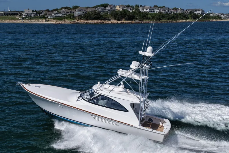 Slide: The Image of 2024 Viking 48 Sport Tower cruising on ocean near coastal homes. - 2