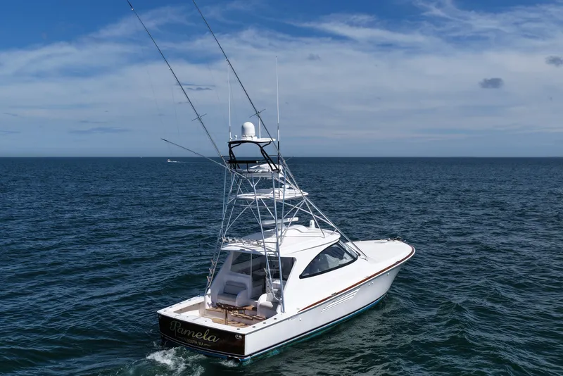 Slide: The Image of 2024 Viking 48 Sport Tower yacht cruising on open sea under blue sky. - 23