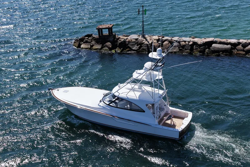 Slide: The Image of 2024 Viking 48 Sport Tower yacht cruising near rocky shoreline. - 27