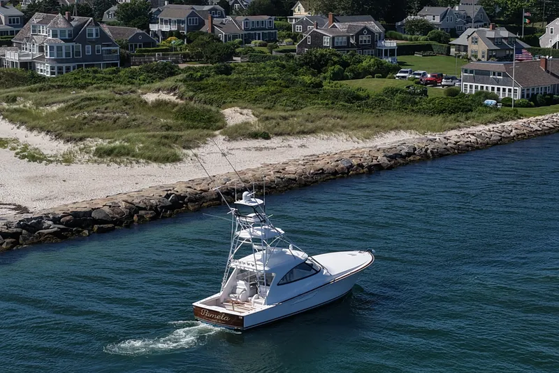 Slide: The Image of 2024 Viking 48 Sport Tower yacht cruising near coastal homes and sandy beach. - 28