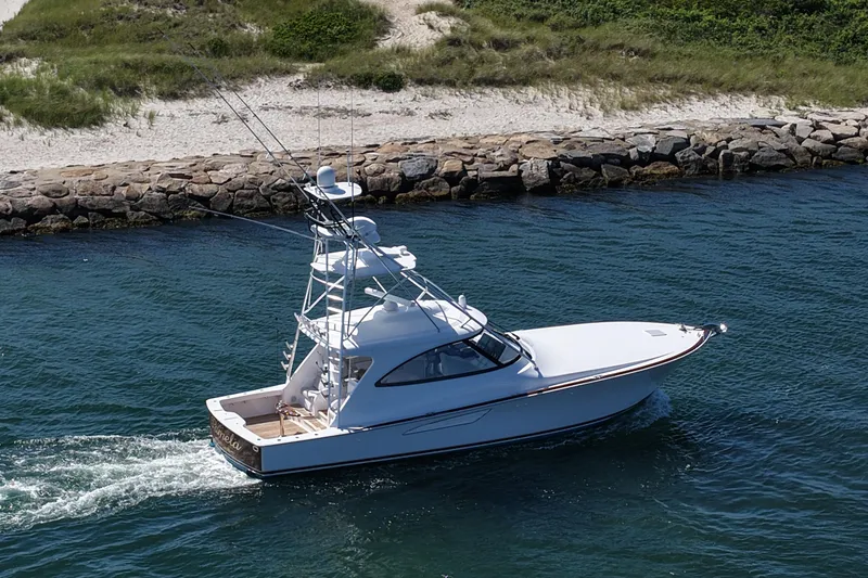 Slide: The Image of 2024 Viking 48 Sport Tower yacht cruising near rocky shoreline. - 29