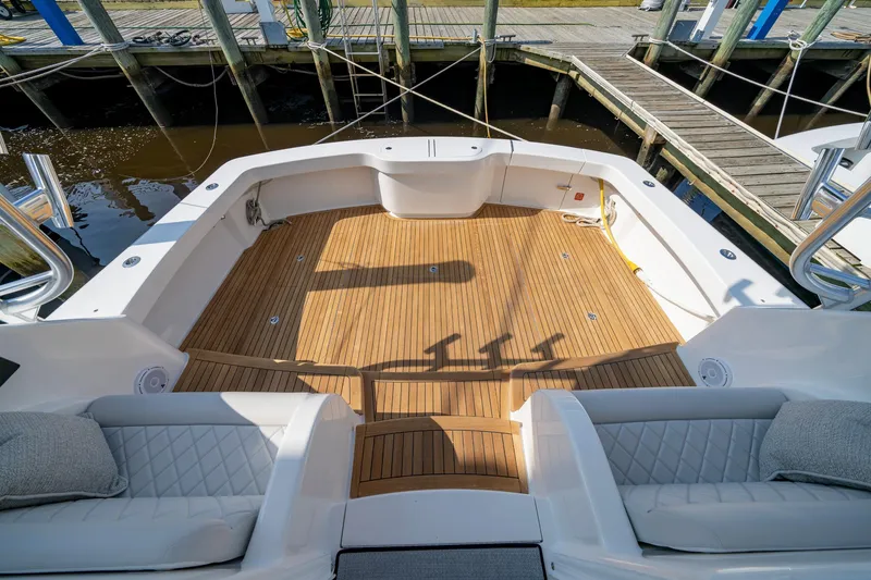 Slide: The Image of 2024 Viking 48 Sport Tower boat deck with teak flooring and cushioned seating. - 46