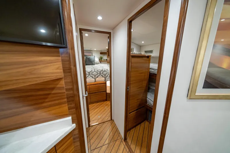 Slide: The Image of 2024 Viking 48 Sport Tower interior with cozy bedroom and bunk beds, featuring elegant wood finishes. - 63