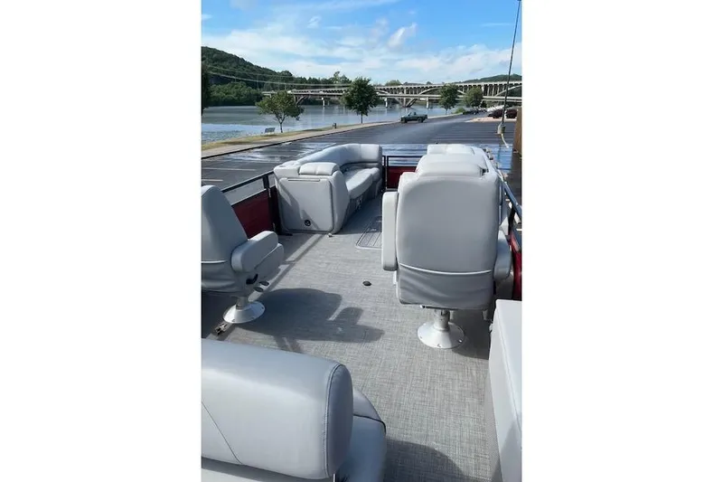 Slide: The Image of 2024 Regency 250 DL3 pontoon boat with gray seating, docked by a scenic river. - 13