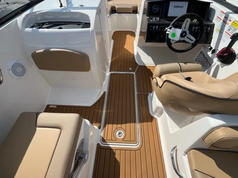 Slide: The Image of 2025 Bayliner VR6 Bowrider OB interior with tan seating and wood-style flooring. - 12