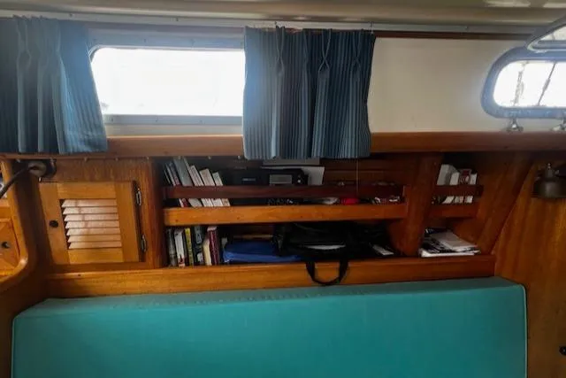 Slide: The Image of Interior of a 1981 Bristol 35.5 sailboat with wooden shelves and teal seating. - 10