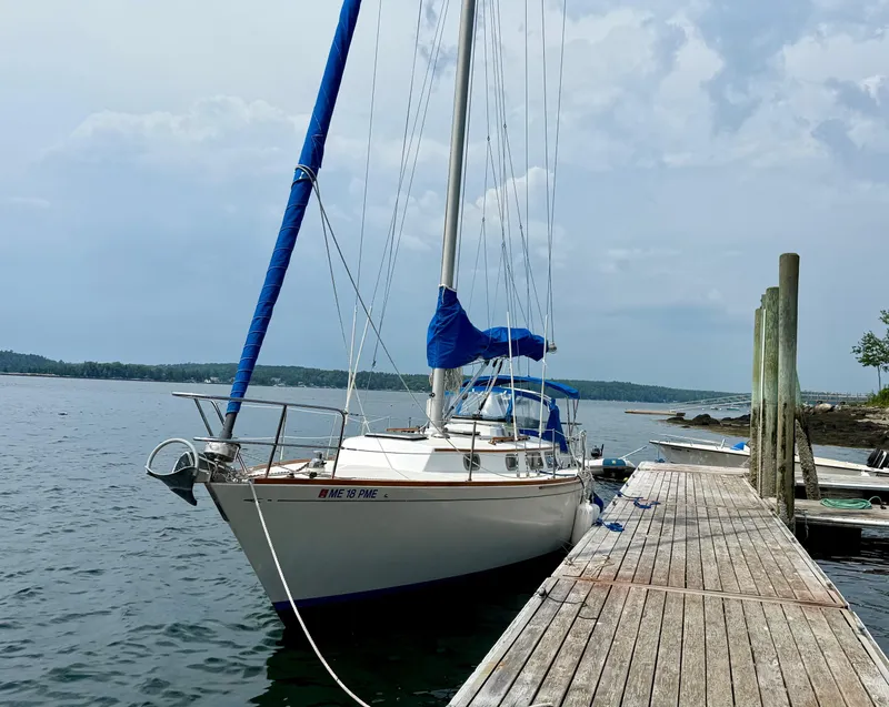 Slide: The Image of Sailboat docked at a wooden pier, Bristol 35.5 model, 1981, with blue sail covers. - 29