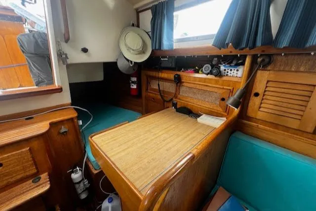 Slide: The Image of 1981 Bristol 35.5 sailboat interior with wooden table, teal cushions, and nautical decor. - 4