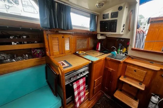 Slide: The Image of 1981 Bristol 35.5 yacht interior with wooden cabinetry, compact kitchen, and blue seating. - 6