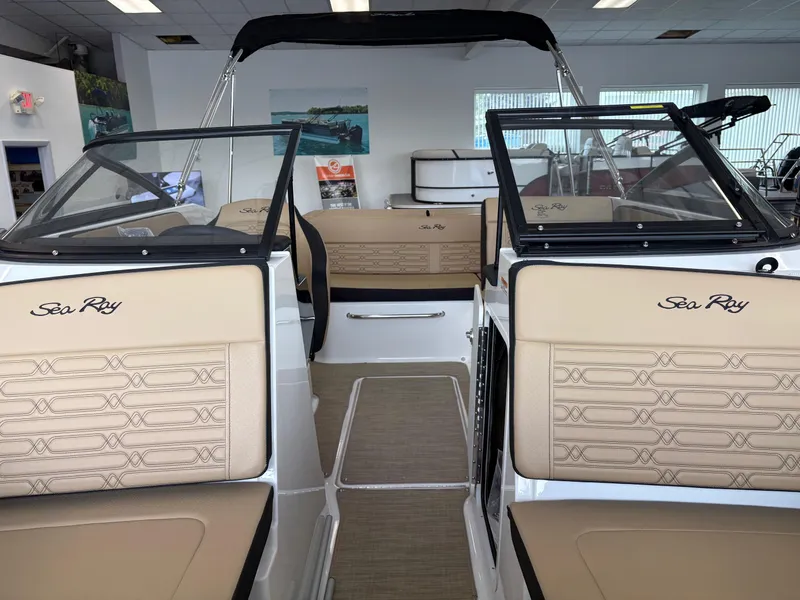 Slide: The Image of 2025 Sea Ray SPX 190 boat interior with beige seating and black accents in showroom. - 9