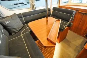 Slide: The Image of 2022 Targa 32 yacht interior with wooden table and black cushioned seating. - 15