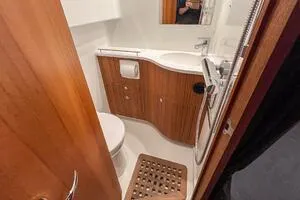 Slide: The Image of 2022 Targa 32 boat bathroom with wooden accents, shower, and sink. - 36
