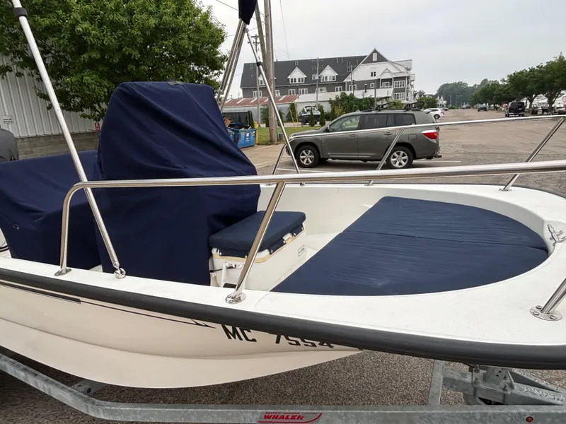 Slide: The Image of 2016 Boston Whaler 150 Montauk boat with blue covers, parked on a trailer. - 10