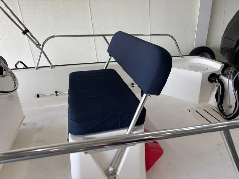 Slide: The Image of 2016 Boston Whaler 150 Montauk boat interior with blue cushioned seating. - 12