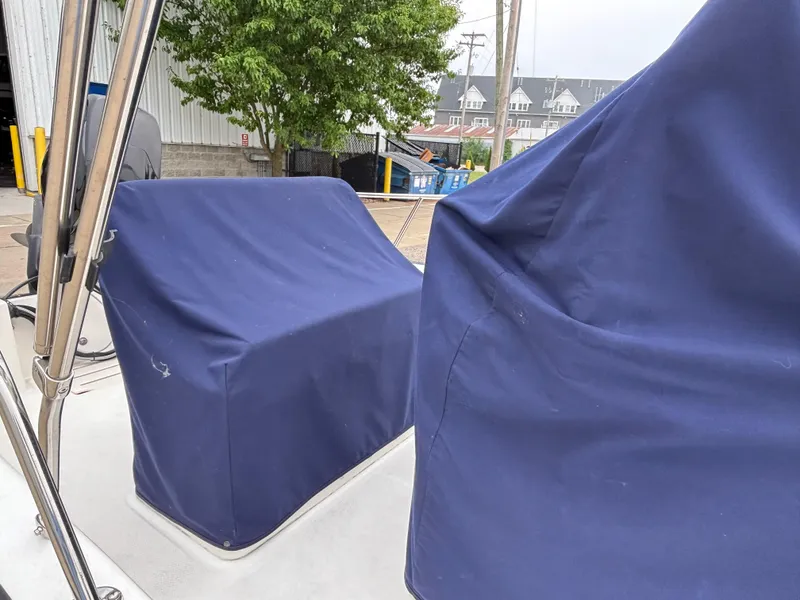 Slide: The Image of 2016 Boston Whaler 150 Montauk with blue protective covers, docked near a building. - 13