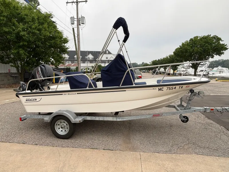 Slide: The Image of 2016 Boston Whaler 150 Montauk boat on trailer, parked outdoors. - 3