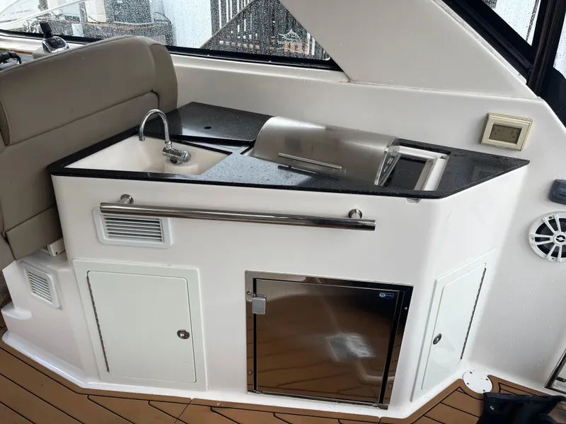 Slide: The Image of 2014 Regal 35 Sport Coupe boat kitchenette with sink, fridge, and storage cabinets. - 21